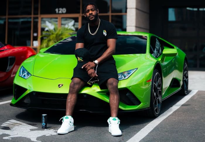 UFC Bantamweight Champion Aljamain Sterling sits on the hood of his Lamborghini.